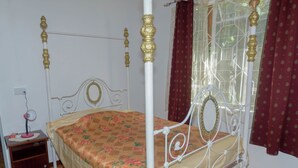 A four-poster bed with a floral bedspread, a bedside table with a lamp, and a window with curtains. - Chic 2-bedroom apartment with WiFi, fitness room in vibrant Vacoas-Phoenix (Vacoas-Phoenix)