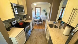 A compact kitchen with white cabinets, a microwave, stove, and a dining area with a table and chairs.