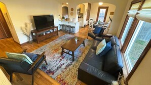 A spacious living area with a sofa, coffee table, and TV. A kitchen is visible in the background.