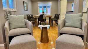 A modern living room with two grey armchairs, a wooden coffee table, and a dining table with chairs. - Luxury Modern Retreat: w/ Sauna & Modern Amenities (Mississauga)