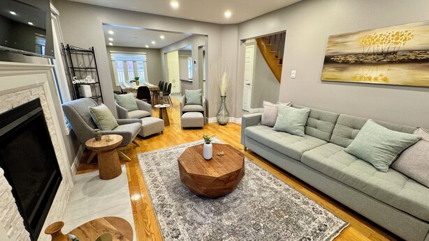 A spacious living room with a fireplace, grey sofas, a coffee table, and a painting on the wall. - Luxury Modern Retreat: w/ Sauna & Modern Amenities (Mississauga)