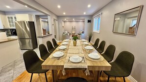 A dining room with a long wooden table set for six, surrounded by dark green chairs. - Luxury Modern Retreat: w/ Sauna & Modern Amenities (Mississauga)