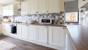 A modern kitchen with white cabinets, a wooden countertop, a built-in oven, and a microwave. - 3br-garden-freeparking-neartowncentre (Ipswich)