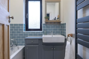 Ein Badezimmer mit einem weißen Waschbecken, einem Fenster und einem Spiegel darüber.