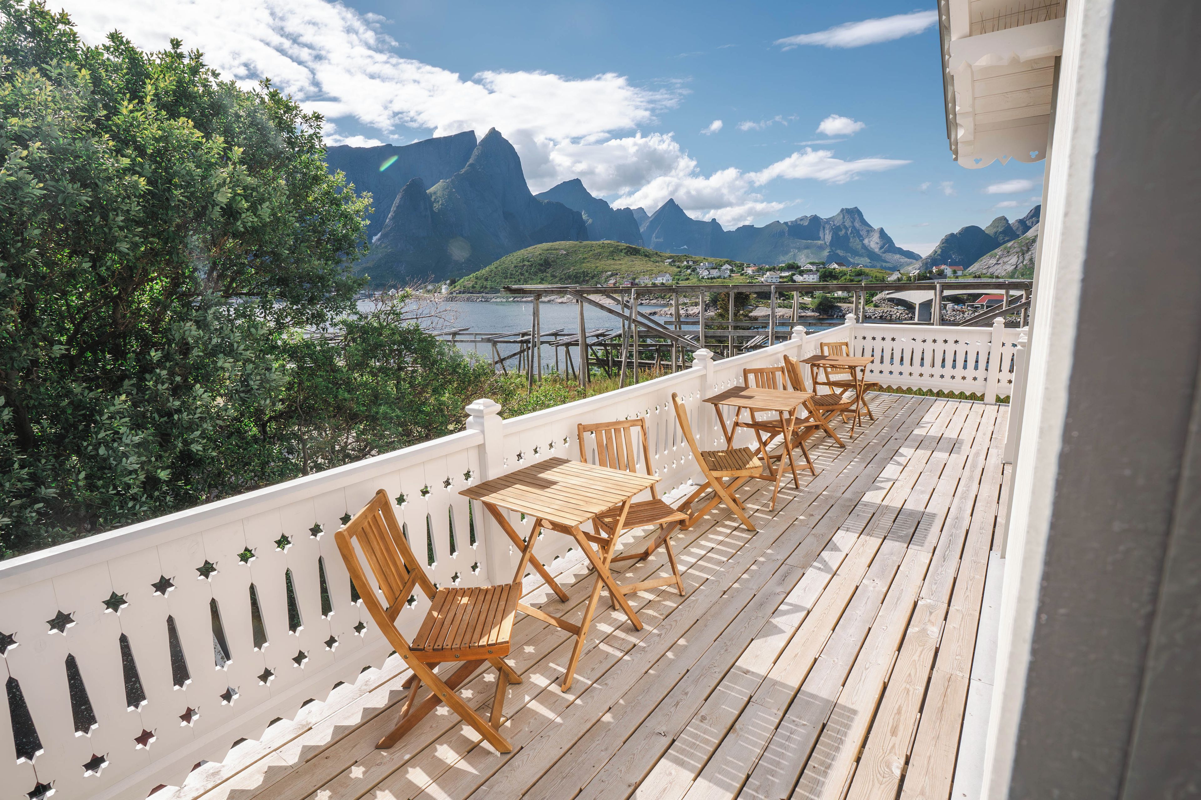 Una terraza de madera con mobiliario exterior, con vista a un fiordo y montañas.