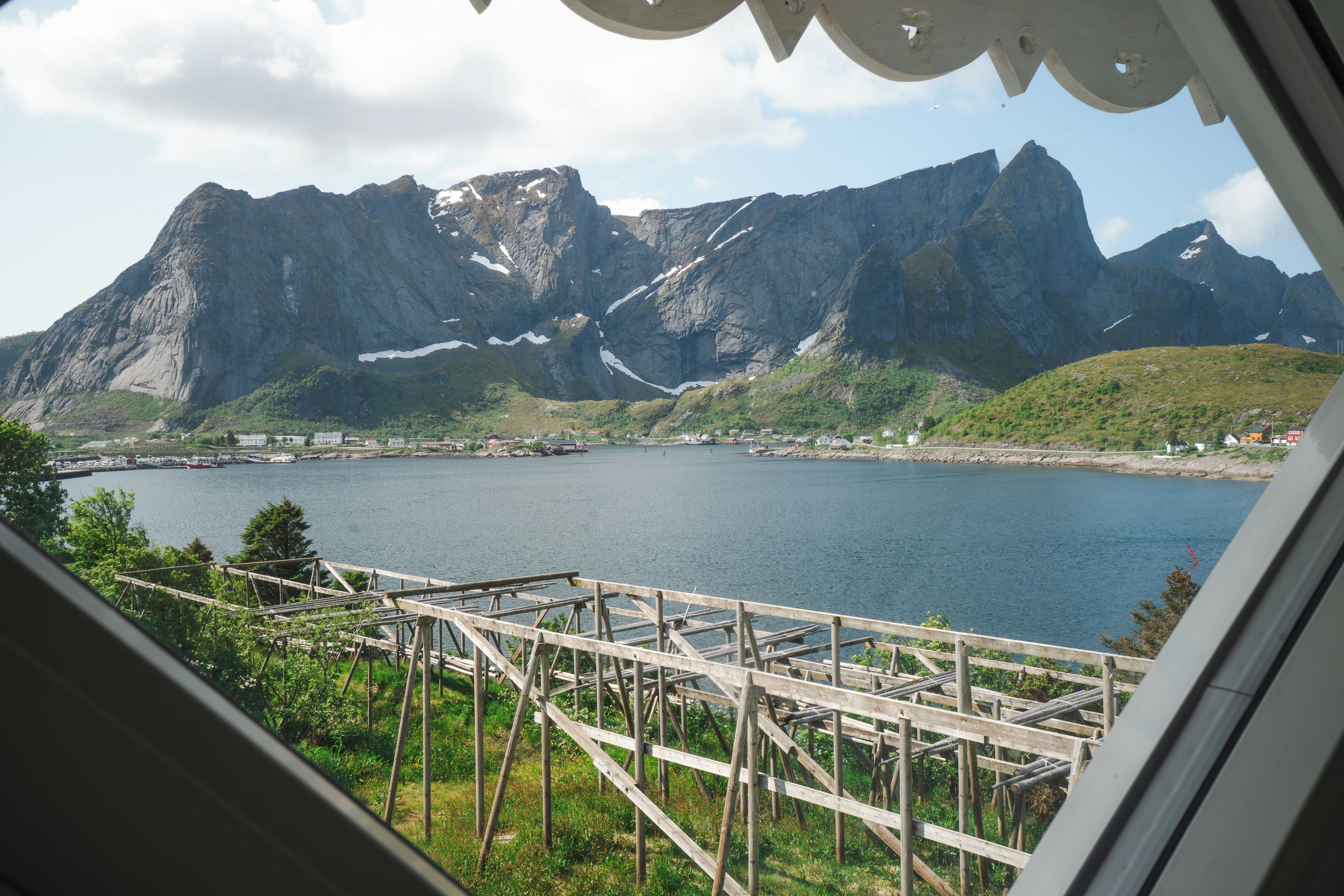 A view of a fjord with mountains in the background and a wooden dock in the foreground.