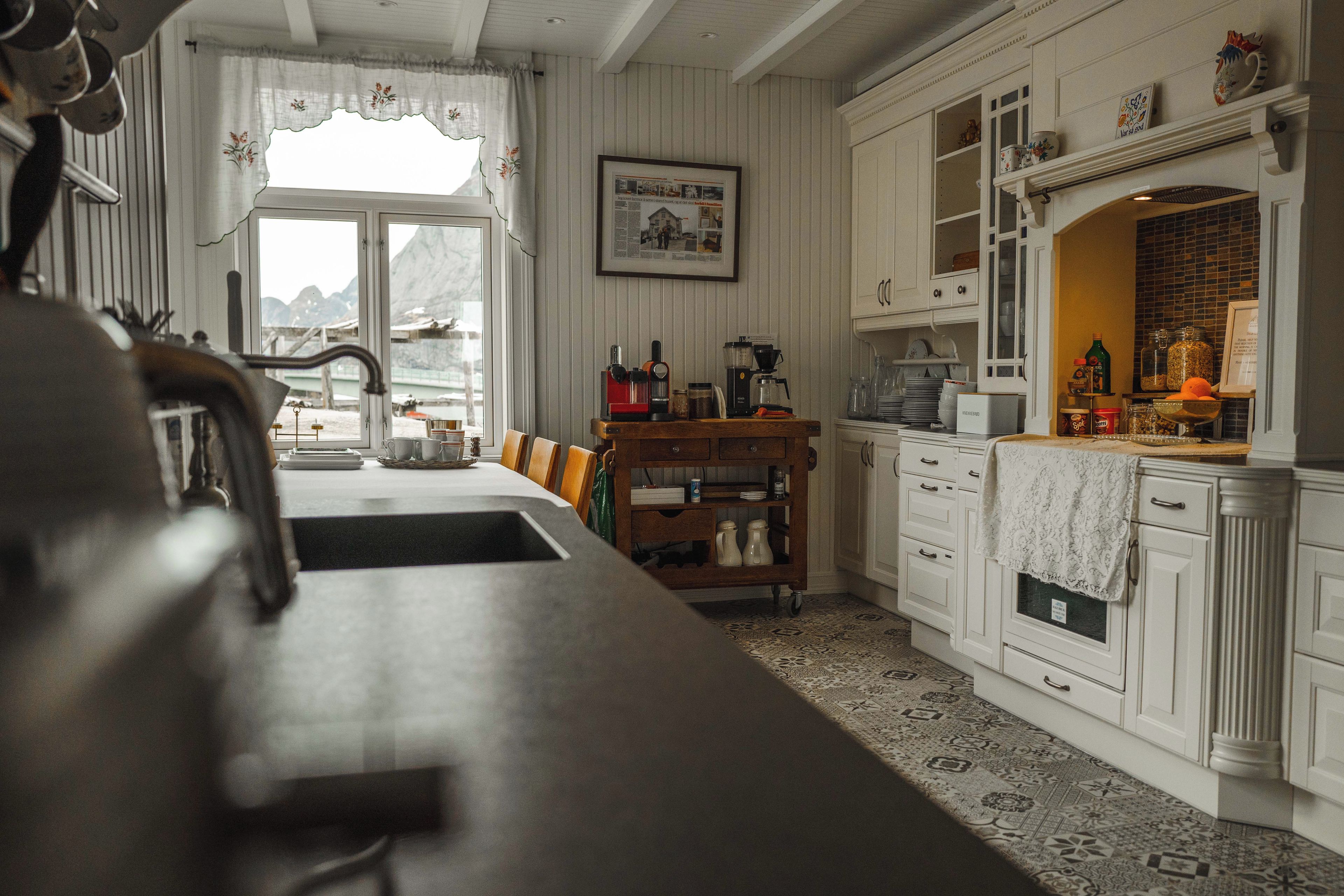 A kitchen with a wooden countertop, a coffee machine, and a view of mountains through the window.