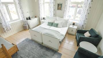 Une chambre à coucher comprenant un lit, des tables de chevet, une commode, une chaise et une fenêtre avec des rideaux.
