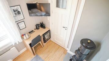 A compact kitchen with a microwave, kettle, and coffee maker on the counter, a small table, and a door with a handle.