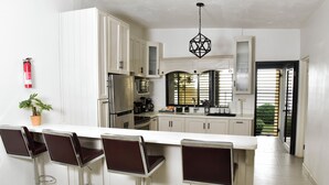 A modern kitchen with white cabinets, stainless steel appliances, and a central island with bar stools.