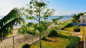 A coastal property with a view of the sea, a fenced garden, and a building with a yellow facade.