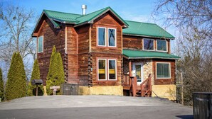 Una baita di legno a due piani con tetto verde, un portico anteriore e una cassetta delle lettere.