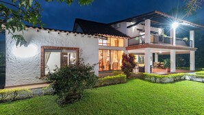 A two-story house with a covered patio and a well-maintained lawn. - Country house-Chalet in El Caimo, Armenia with private pool and BBQ (El Caimo)