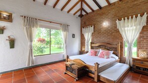 A bedroom with a wooden bed, a small bedside table, a nightstand, and a window with curtains. - Country house-Chalet in El Caimo, Armenia with private pool and BBQ (El Caimo)