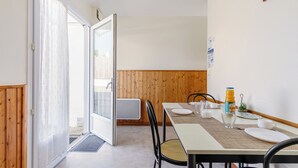 Ein Essbereich mit einem Tisch für zwei Personen, einer Holzwand und einer zur Außenseite führenden Tür.
