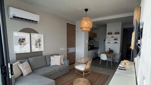 Un soggiorno moderno con un divano grigio, una poltrona in vimini e un tappeto intrecciato.