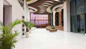 Un'ampia hall con un design moderno del soffitto, grandi finestre e piante da interno.