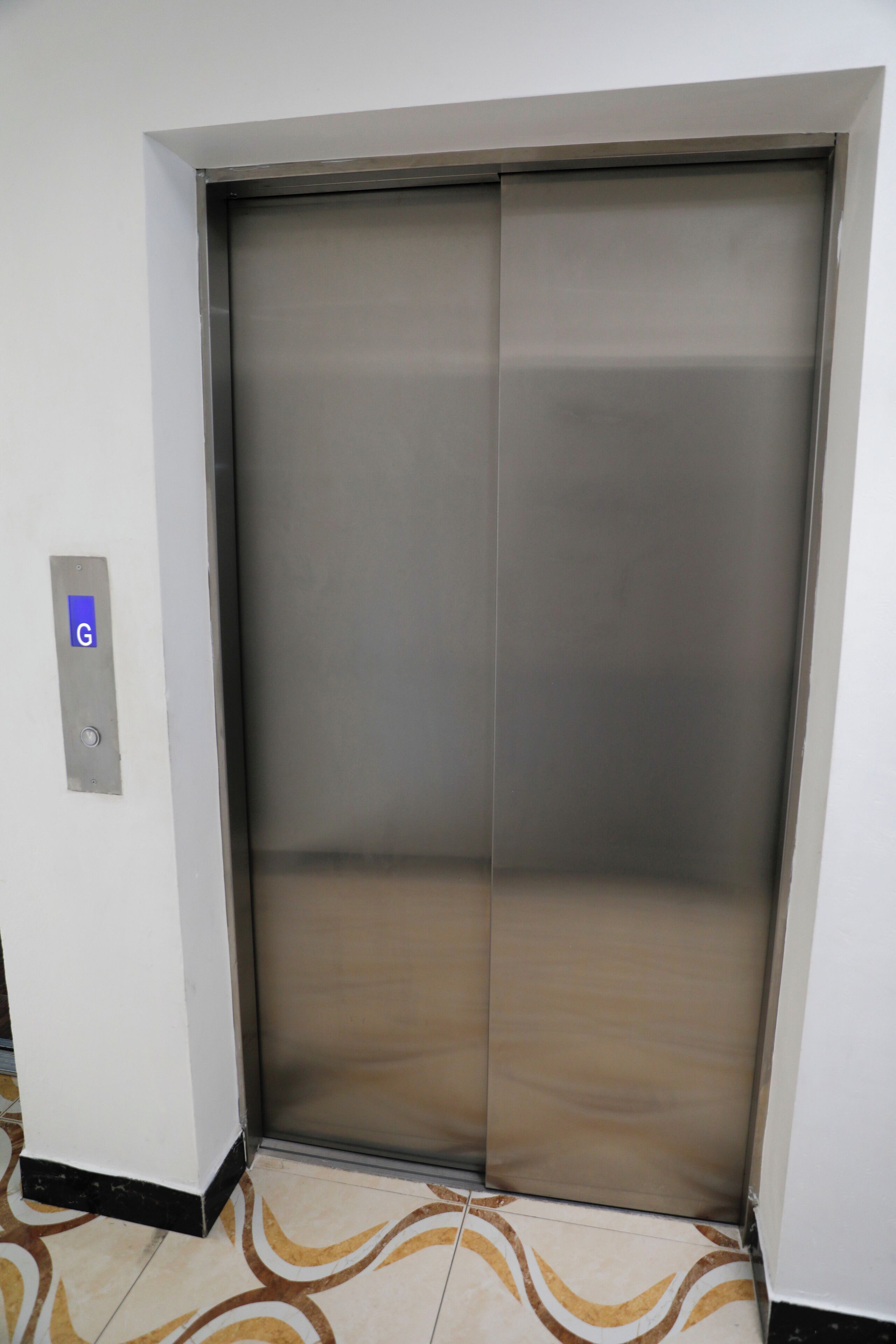 A closed elevator with a metallic finish and a control panel with a 'G' button.