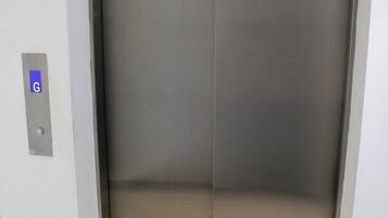 A closed elevator with a metallic finish and a control panel with a 'G' button.
