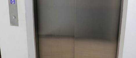 A closed elevator with a metallic finish and a control panel with a 'G' button.