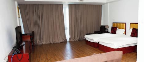 Een hotelkamer met een bed, bureau, stoel, televisie en plafondventilator.