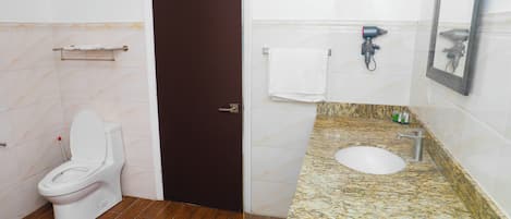 A bathroom with a toilet, sink, towel rack, and a door.