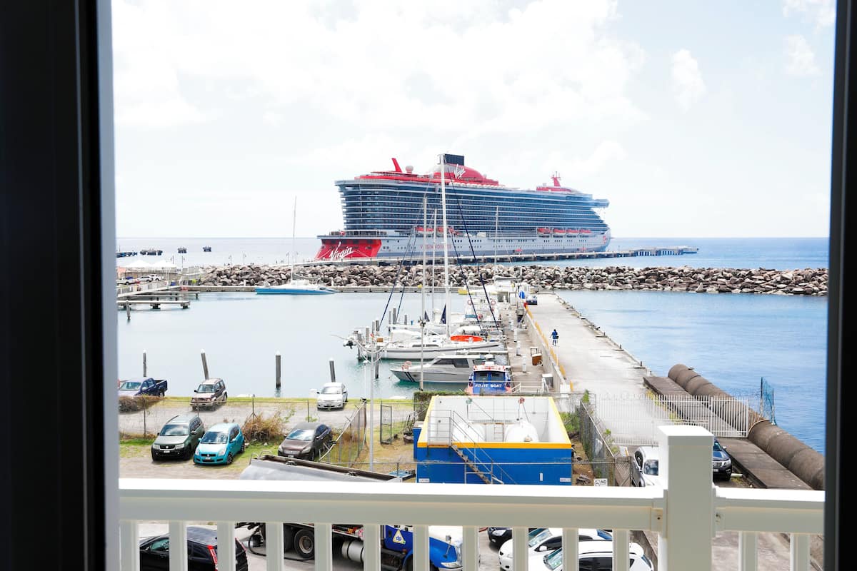 Un crucero amarrado en un puerto deportivo con varios barcos y coches cerca.