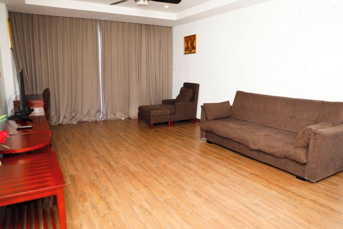 Una sala de estar con un sofá marrón, una mesa roja y un ventilador de techo.