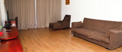 A living room with a brown sofa, a red table, and a ceiling fan.