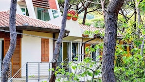 A house with a tiled roof, wooden shutters, and a balcony with a metal railing.