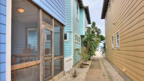 Un étroit passage bordé de deux bâtiments dotés de grandes fenêtres et d’un petit espace patio.