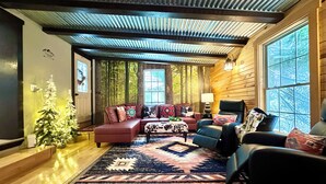 A cozy living room with a sectional sofa, a patterned rug, and a small Christmas tree.