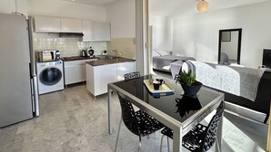 Une cuisine moderne avec un coin repas, un lave-linge et une petite table avec des chaises.