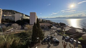 Un paysage urbain côtier avec un parking, des bâtiments et une vue dégagée sur la mer.