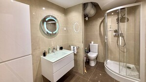 Une salle de bain moderne avec un meuble-lavabo, des toilettes et une douche à parois de verre.