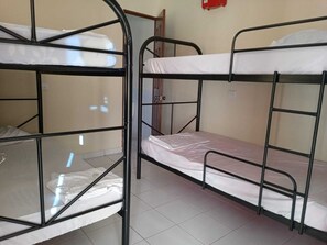 A dormitory room with bunk beds, a tiled floor, and a door with a handle. - Hostal Mansión Histórica (Santa Ana)