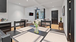 A modern dining area with a table set for two, a vase with flowers, and a television mounted on the wall. - Brasilito 1 (Brasilito)