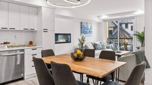 Una cocina moderna con armarios blancos, una mesa de comedor de madera y una chimenea empotrada.
