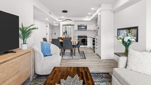 Una sala de estar moderna con televisor de pantalla plana, un sofá, una mesa de centro y un comedor con mesa y sillas.