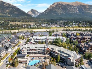 A resort with multiple buildings, a swimming pool, and a view of mountains. - Sleeps 8! 1003sqft Loft + Pool, Hot Tub Near Banff (Canmore)