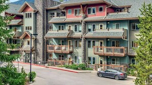 Un hotel de varios pisos con balcones y montañas al fondo.