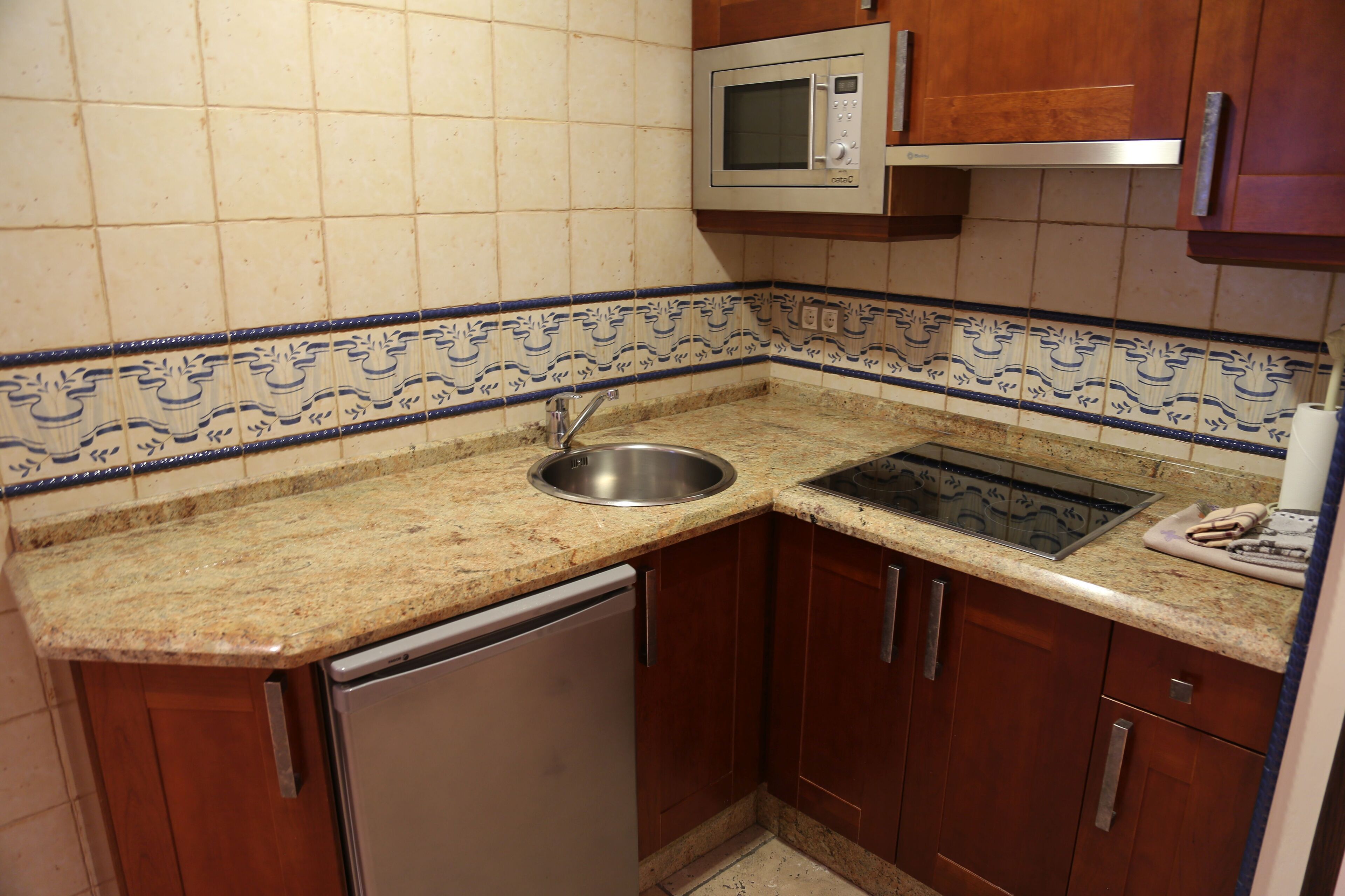 A compact kitchen with a sink, microwave, and stainless steel dishwasher.