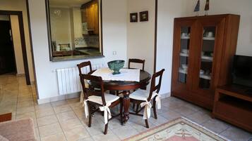 Een eetgedeelte met een ronde tafel, stoelen, een grote spiegel en een kast met glazen deuren.
