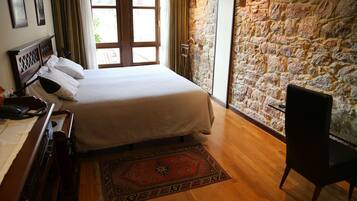 Un dormitorio con cama, escritorio de madera, silla y pared de piedra.