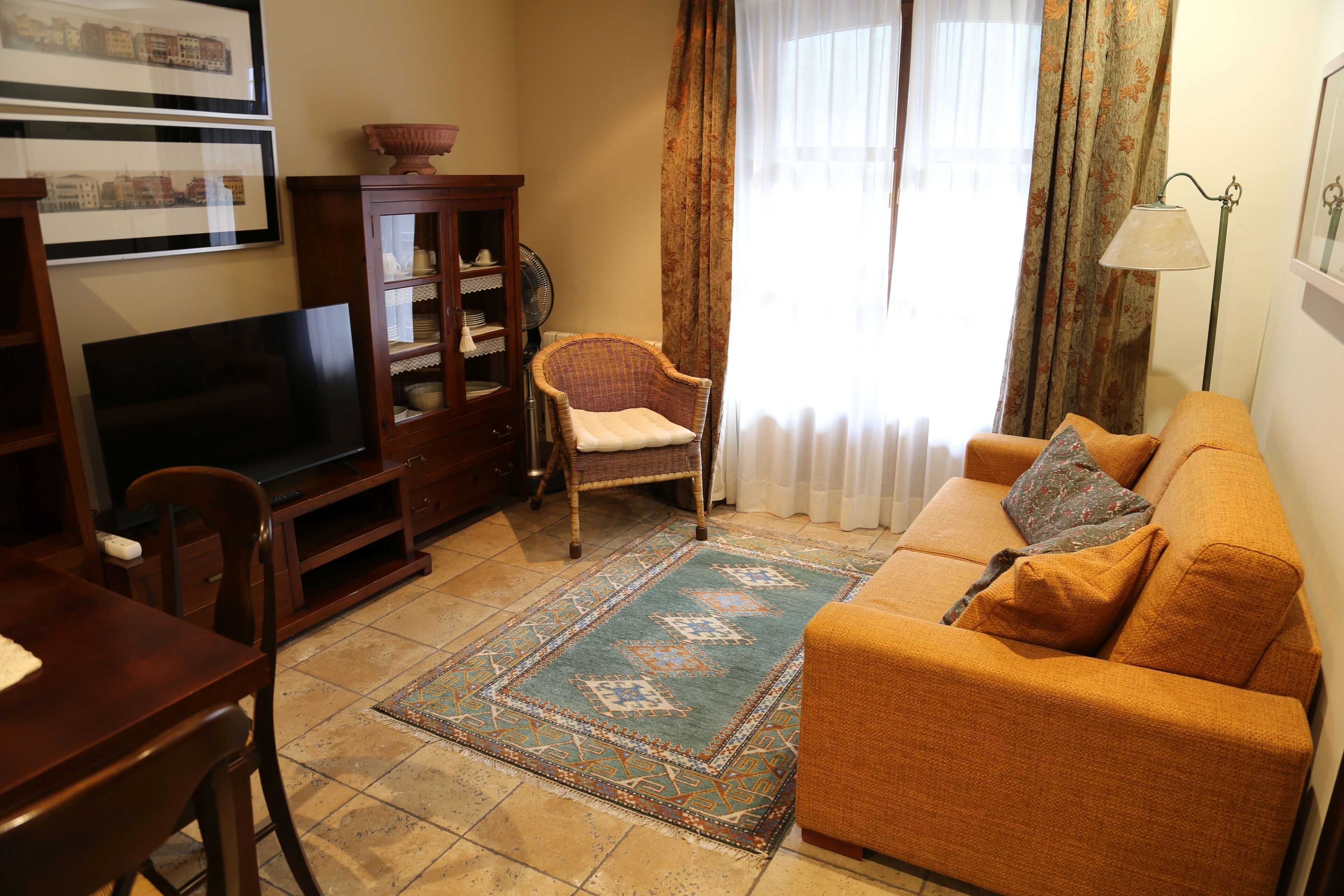 A living room with a sofa, a television, a cabinet, a chair, and a patterned rug.