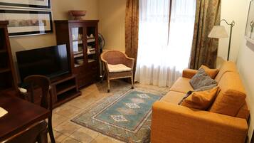 A living room with a sofa, a television, a cabinet, a chair, and a patterned rug.