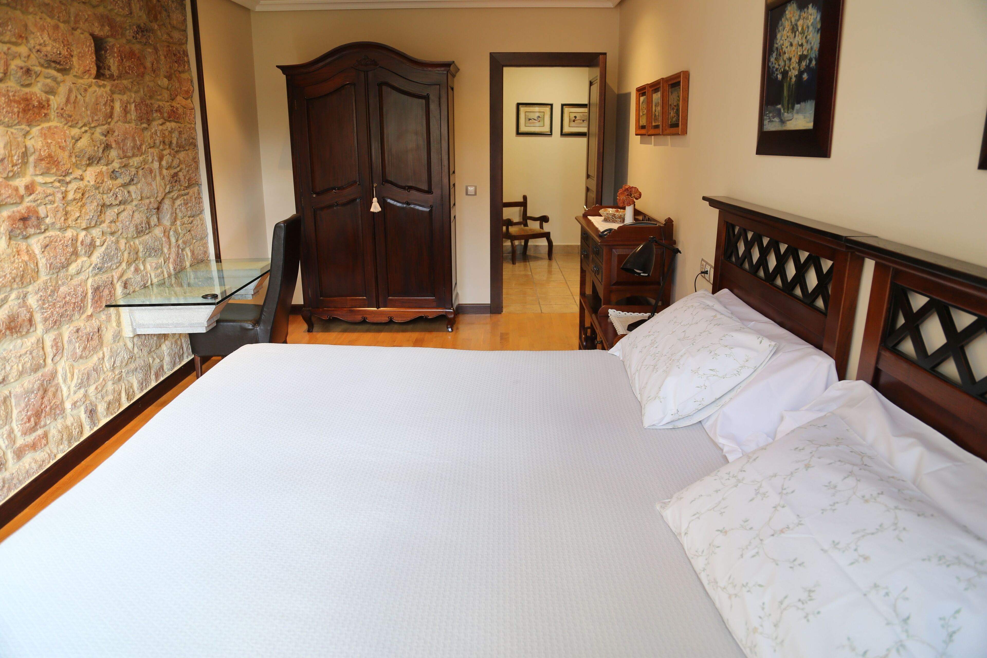 Un dormitorio con una cama grande, un armario de madera y un escritorio con una silla.