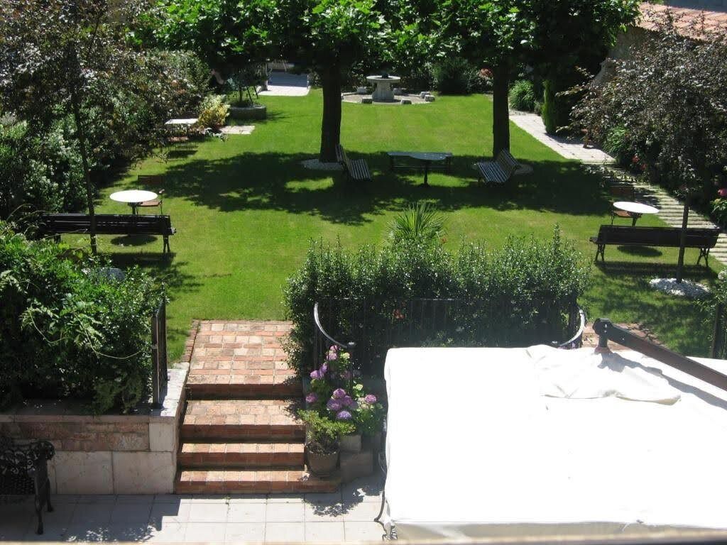 A courtyard with a lawn, benches, and a brick staircase leading to a covered area.