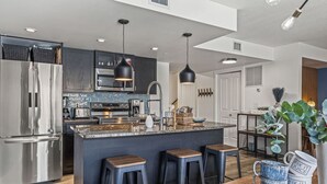 Une cuisine moderne dotée d’un îlot central, d’appareils électroménagers en acier inoxydable et de tabourets de bar.