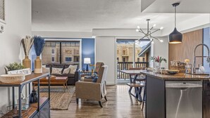 Une cuisine moderne dotée d’un îlot central, un coin repas offrant une vue sur l’extérieur et un salon avec un canapé et une table basse.